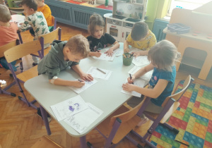 Dzieci wykonują karty pracy do zeszytu o emocjach