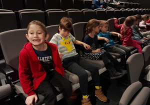 Dzieci siedzą na fotelach w teatrze