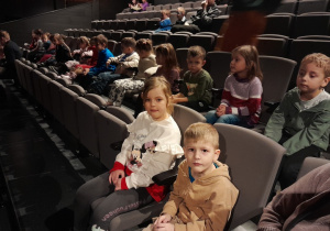 Dzieci siedzą na fotelach w teatrze