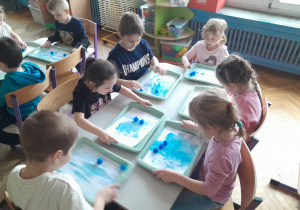 Dzieci malują kartkę kostkami lodu