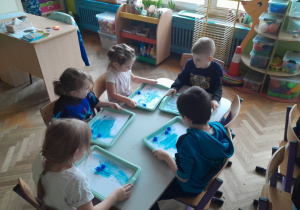 Dzieci malują kartkę kostkami lodu