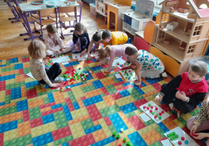 Dzieci układają nakrętki na planszy