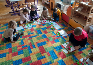 Dzieci układają nakrętki na planszy