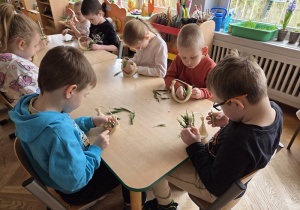 dzieci tworzą koszyczki z sizalu