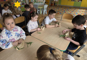 dzieci tworzą koszyczki z sizalu