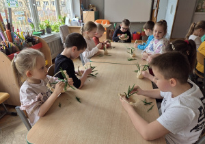 dzieci tworzą koszyczki z sizalu