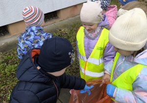 dzieci sprzataja wokol przedszkola