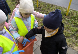 dzieci sprzataja wokol przedszkola