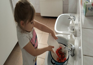 dziewczynka wsypuje do durszlaka pomidorki