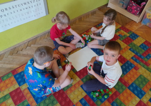 Dzieci układają literę "r" z nakrętek