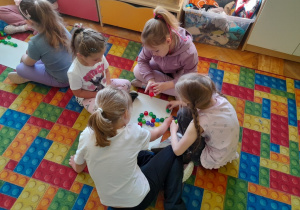 Dzieci układają literę "r" z nakrętek