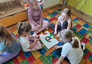 Dzieci układają literę "r" z nakrętek