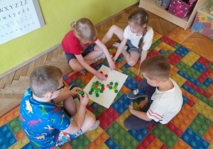 Dzieci układają literę "r" z nakrętek