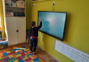 Dzieci piszą na tablicy poznaną literę