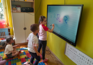 Dzieci piszą na tablicy poznaną literę