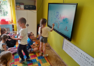 Dzieci piszą na tablicy poznaną literę