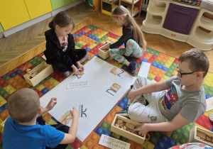 przedszkolaki układają głoski z drewnianych klocków