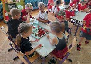 Dzieci odrywają szypułki z truskawek