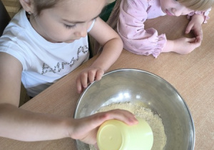 Dziewczynka wsypuje do miski mąkę