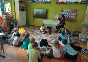 Dzieci słuchają książki czytanej przez Panią Bibliotekarkę