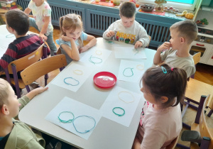 Dzieci układają literę "O" ze sznurka