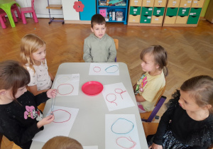 Dzieci układają literę "O" ze sznurka