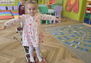 dzieci tworzą jesienną ścieżkę sensoryczną
