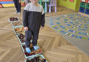 dzieci tworzą jesienną ścieżkę sensoryczną