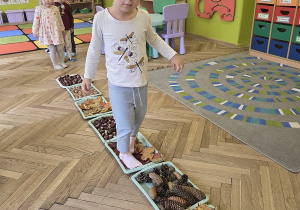 dzieci tworzą jesienną ścieżkę sensoryczną