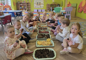 dzieci tworzą jesienną ścieżkę sensoryczną