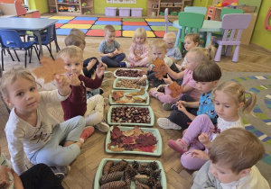 dzieci tworzą jesienną ścieżkę sensoryczną