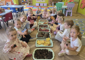 dzieci tworzą jesienną ścieżkę sensoryczną