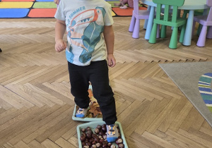 dzieci tworzą jesienną ścieżkę sensoryczną