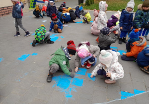Dzieci tworzą mural chodnikowy z okazji Dnia Praw Dziecka