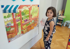 Dziewczynka przykleja pierwsze warzywo na plakat projektowy