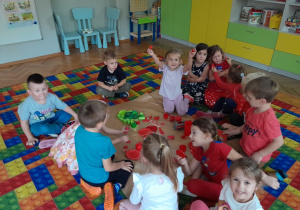 Dzieci prezentują pomidora ułożonego z zabawek w odpowiednich kolorach