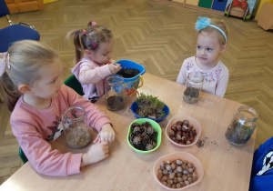 Dzieci tworzą las w słoiku z przyniesionych materiałów przyrodniczych