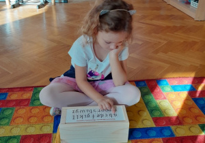 Dziewczynka wskazuje poznaną literę na planszy