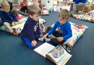 Chłopcy oglądają książki w bibliotece