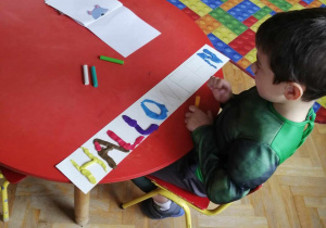 Chłopiec wypełnia napis po angielsku za pomocą plasteliny