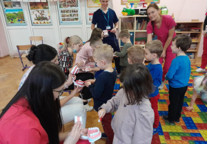 Dzieci pokazują na modelu szczęki, w jaki sposób myć zęby