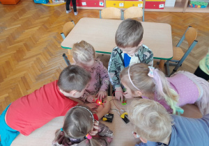 Dzieci podejmują próby stworzenia prostego obwodu elektrycznego z użyciem baterii i diody