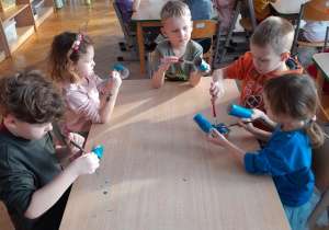 Dzieci malują farbami papierowe rolki