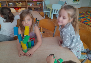 Dzieci tworzą budowle z papierowych klocków