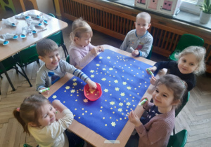 Dzieci tworzą grupową pracę plastyczną związaną z kosmosem