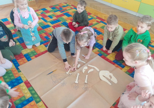 Dzieci układają duży szkielet dinozaura