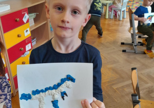 Chłopiec prezentuje ulepionego przez siebie dinozaura