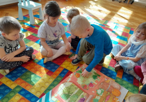 Dzieci przyklejają sylwetę szpinaku na plakat projektu "Witaminki"