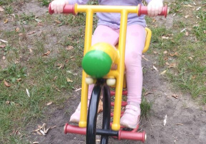 Dziewczynka jeździ na motorku.