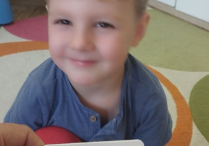 Chłopiec naśladuje daną emocję z obrazka.